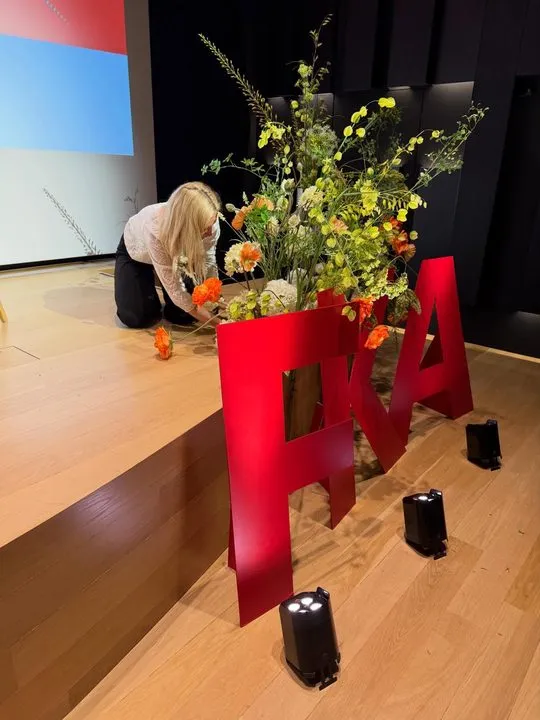 Ásta stillir upp blómaskreytingu á sviði fyrir FKA-viðburð